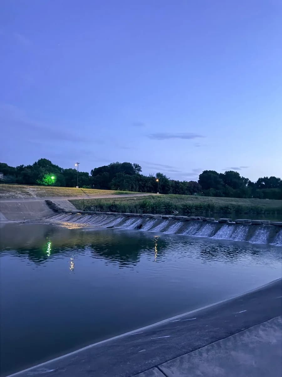 The Trinity River weir at dusk, water stepping over the concrete